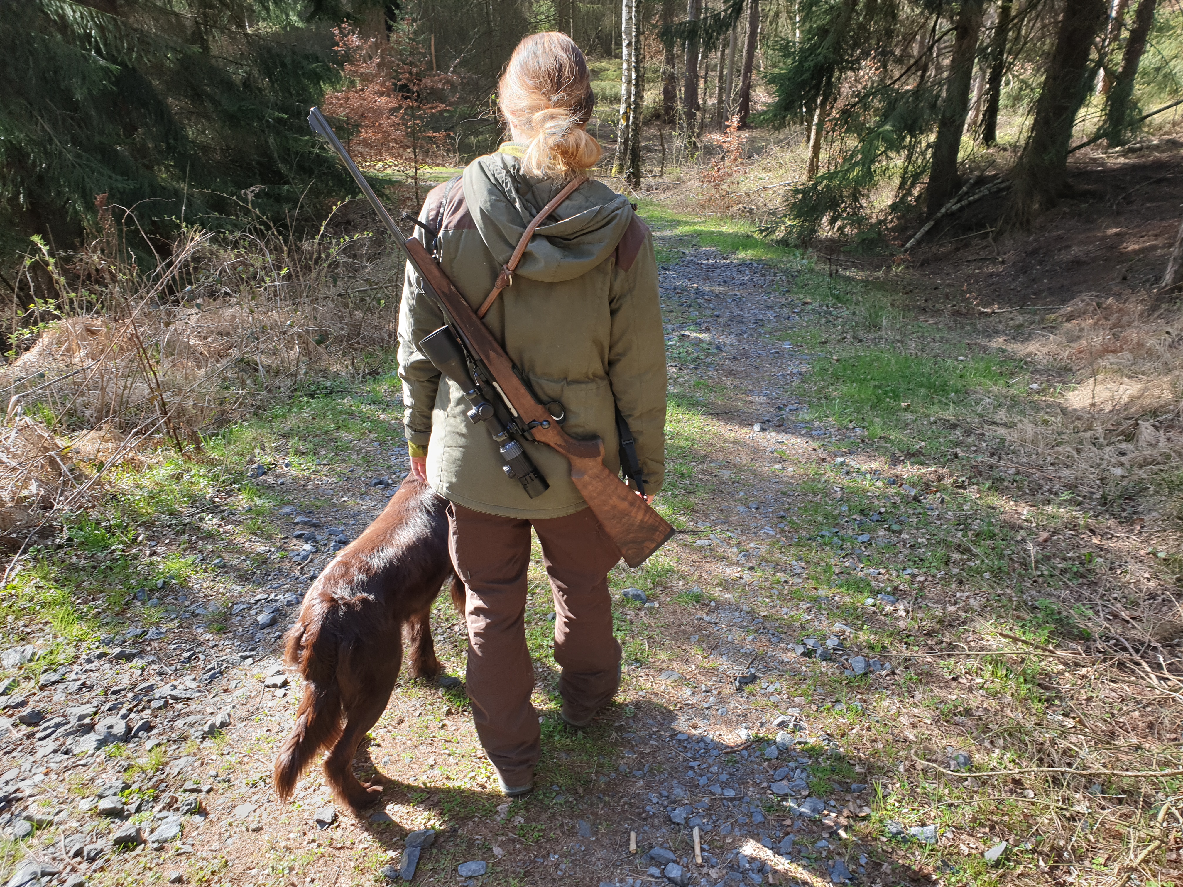 Anna mit Hund auf einem Waldweg, Rückenansicht
